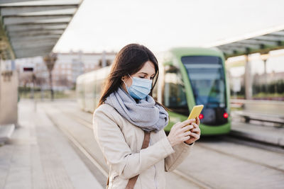 Woman standing on mobile phone in city