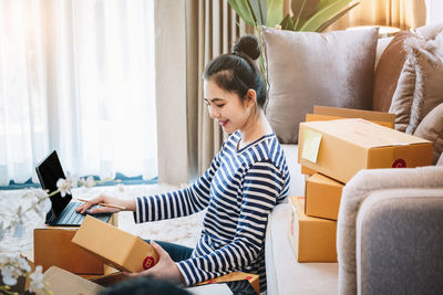 Mother using digital tablet while sitting on sofa at home