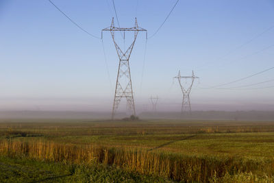 Electricity pylon on field against sky