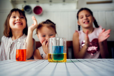 Three cute children play in the kitchen at home with colored liquids. experiments with color at home