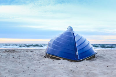 Deck chairs on beach against sky