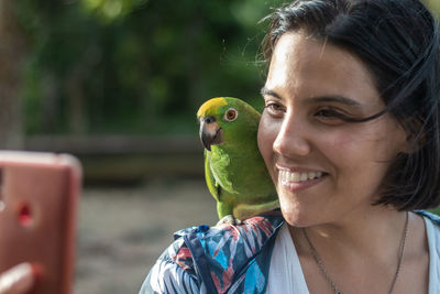 Woman performs a selfie with a parrot in the jungle of the orinoco delta in venezuela