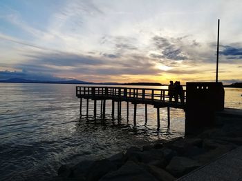 Pier over lake against sky during sunset
