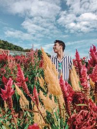 Man standing amidst flowering plants against sky