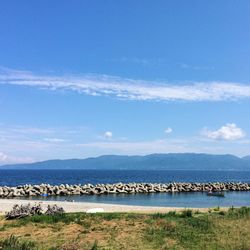 Groynes amidst lake against sky on sunny day