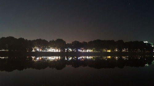 Reflection of trees in calm lake at night