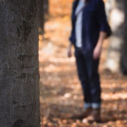 Man standing by tree trunk in forest