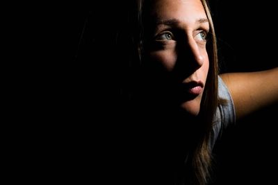 Close-up of young woman against black background