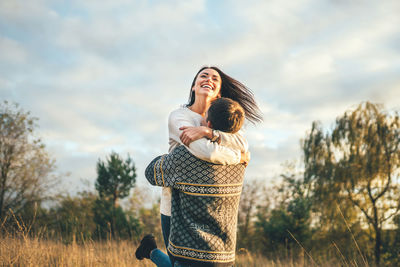 Woman with arms raised on field against sky