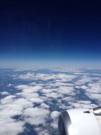 Cropped image of airplane wing over clouds