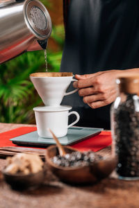 Midsection of woman filtering coffee in cafe