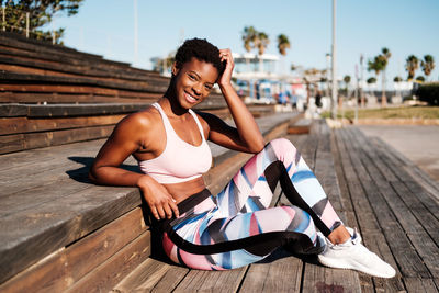 Full length of young woman sitting on wood