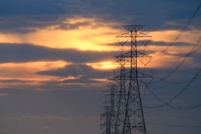 Low angle view of silhouette electricity pylon against sky during sunset