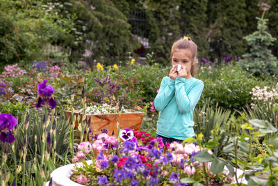 Allergy. a girl shocked by an allergic reaction to flowers near a flowerbed.