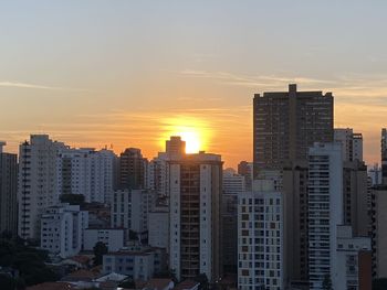Modern buildings in city against sky during sunset