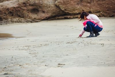 Full length of woman crouching at beach