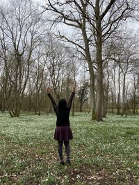 Happy woman standing in the forest with snowdrops flowers in spring background 