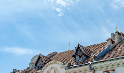 Roof of old building. tiles, small wooden viewing windows, stone chimneys. golden cross