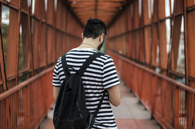 Rear view of man standing on footbridge