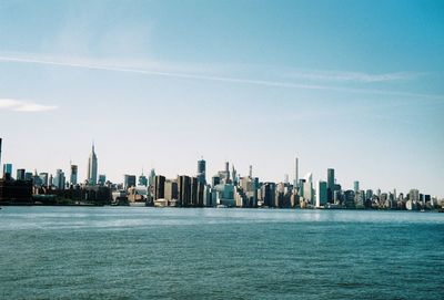 Sea and buildings in city against sky
