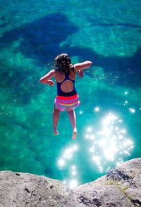 Full length of teenage girl jumping in lake taupo from rock