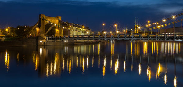 Illuminated bridge over river at night