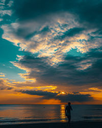 Silhouette person looking at sea against sky during sunset