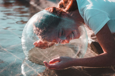 Close-up of woman wearing glass container at lake