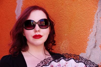 Close-up portrait of young woman standing against wall