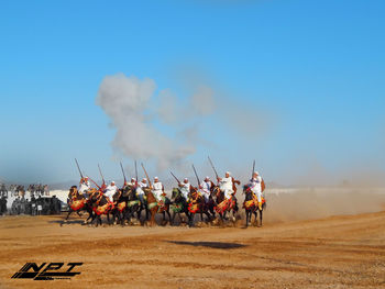 People riding motorcycle on field against sky