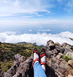 Low section of person on rock against sky