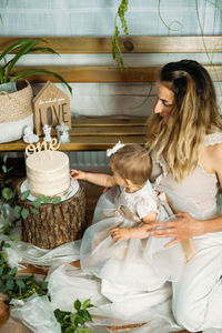 High angle view of mother with daughter sitting by cake at home