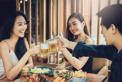 Young friends toasting drinks at restaurant