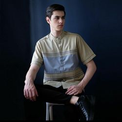 Portrait of young man sitting against black background