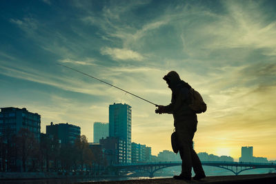 Silhouette man fishing at sunset