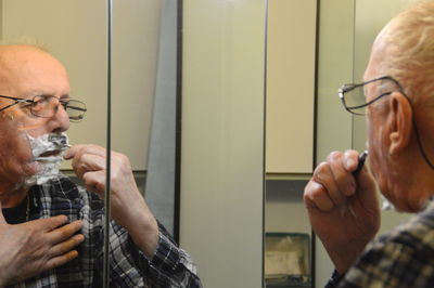 Senior man shaving his face in bathroom