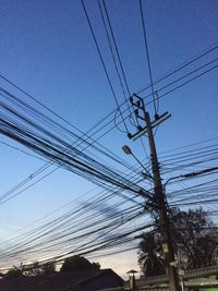 Low angle view of electricity pylon against blue sky