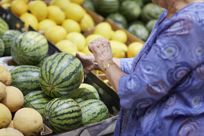 Woman choosing watermelon in shop