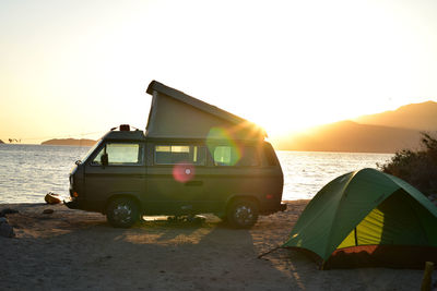 Pop-up camper van and tent silhouetted against sunrise sky in baja, mexico