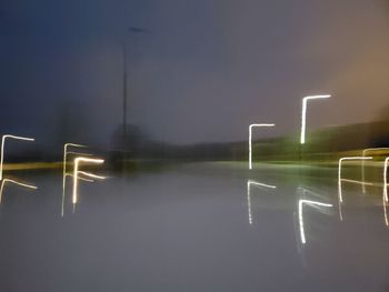 Scenic view of illuminated street against sky at night