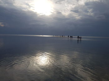 Silhouette people on beach against sky