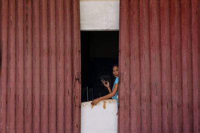 Side view of young woman standing against wall