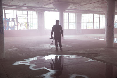 Rear view of silhouette man walking in abandoned building