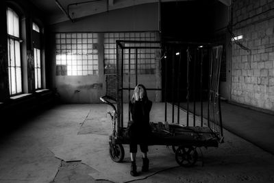 Full length of woman sitting in abandoned building