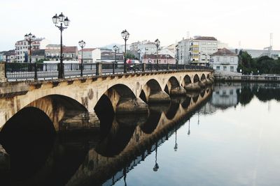 Arch bridge over river against sky in city