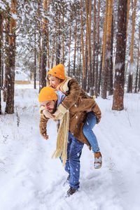 Young couple standing under snow covered tree