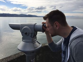 Man looking through coin-operated binoculars by sea
