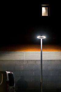 Illuminated street light against wall in city