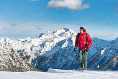 Full length of woman standing on snowcapped mountain against sky
