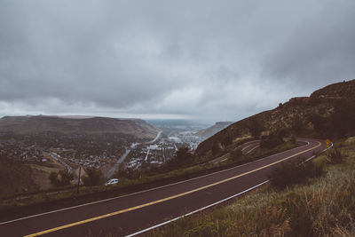 Road by mountains against sky